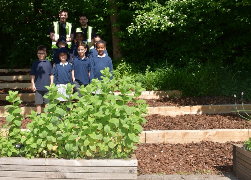 Children on the new playground timbers installed by Lords, with Lords workers